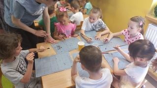 Dzieci próbują namalować pędzlem i wodą poznany znak.