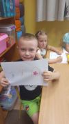 Chłopiec prezentuje namalowany kredkami znak.
